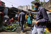 People wearing face mask as a precautionary measure against the coronavirus buy vegetables inside a narrow alley in Kolkata, India, Sunday, Nov. 22, 2020. (AP Photo/Bikas Das)