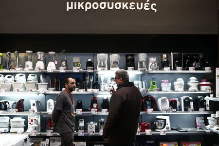 FILE PHOTO: Employee of Electroniki retail chain Stamatis Kyriakos (L) listens to a customer at an Electroniki shop in Athens November 27, 2014. REUTERS/Alkis Konstantinidis