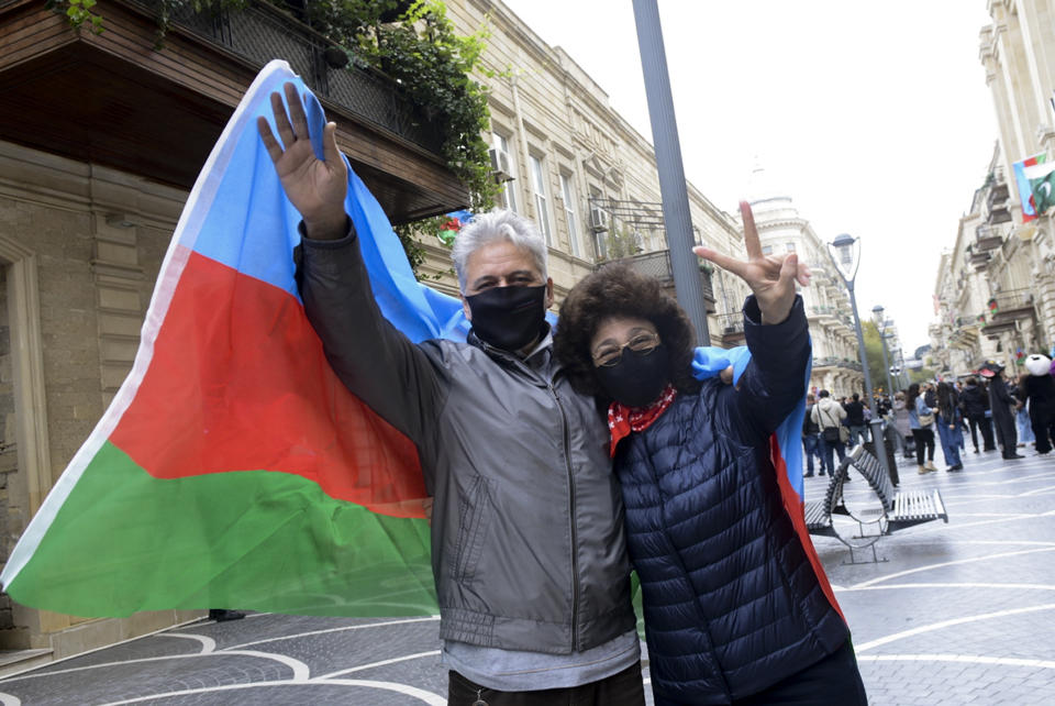 Azerbaijanis with the national flag celebrate after the country's President claimed Azerbaijani forces have taken Shushi, a key city in the Nagorno-Karabakh region that has been under the control of ethnic Armenians for decades in Baku, Azerbaijan, Sunday, Nov. 8, 2020. (AP Photo)