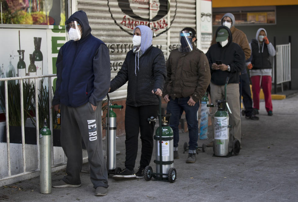 People line up with empty oxygen tanks to refill for family members sick with COVID-19 outside an oxygen store where dozens wait their turn in Mexico City, Thursday, Dec. 31, 2020. (AP Photo/Marco Ugarte)