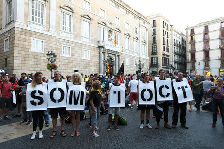 People hold placards that read, "We are October 1", as they stage a sit-in during an occupation of the Sant Jaume square, as a part of events planned to mark the first anniversary of the banned independence referendum held in the region on October 1, 2017, in front of the Catalan regional government headquarters in Barcelona, Spain, September 29, 2018. REUTERS/Jon Nazca