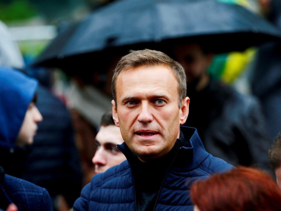 Alexei Navalny wearing a blue jacket surrounded by people.