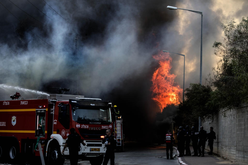 Firefighters deploy after a factory hit by a rocket caught fire in Sderot, southern Israel , Israel, Tuesday, Nov. 12m 2019. Israel has killed a senior Islamic Jihad commander in Gaza in a rare targeted killing that threatened to unleash a fierce round of cross-border violence with Palestinian militants. (AP Photo/Tsafrir Abayov)