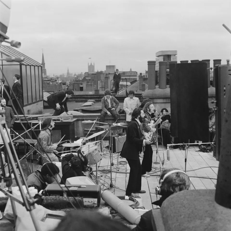 British rock group the Beatles performing their last live public concert on the rooftop of the Apple Organization building for director Michael Lindsey-Hogg&#39;s film documentary, &#39;Let It Be,&#39; on Savile Row, London, UK, 30th January 1969; drummer Ringo Starr sits behind his kit, singer-songwriters Paul McCartney and John Lennon (1940 - 1980) perform at their microphones, and guitarist George Harrison (1943 - 2001) stands behind them. Lennon&#39;s wife Yoko Ono sits at right. (Photo by Evening Standard/Hulton Archive/Getty Images)