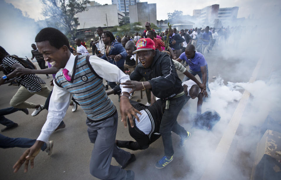 Opposition supporters flee from tear gas grenades fired by riot police, during a protest in downtown Nairobi, Kenya, May 16, 2016. Kenyan police have tear-gassed and beaten opposition supporters during a protest demanding the disbandment of the electoral authority over alleged bias and corruption. (AP Photo/Ben Curtis)
