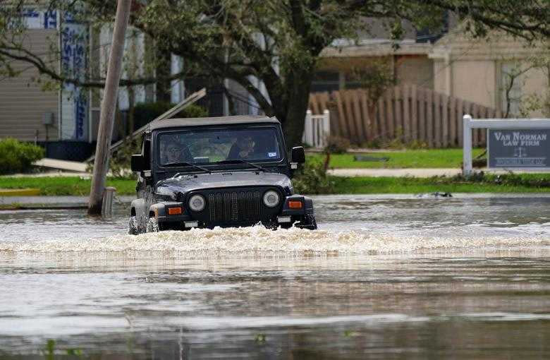 民眾冒險開著皮卡涉水而過。（圖／Reuters）