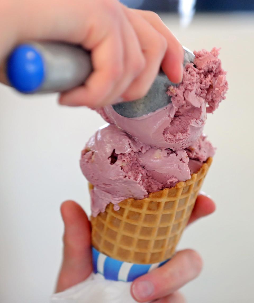 A worker scoops up double dark raspberry for a customer at Pav's Creamery, Sunday, April 16, 2023, in Coventry Township, Ohio.