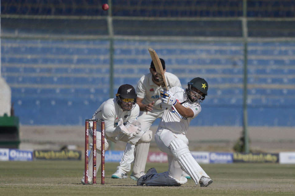 Pakistan's Saud Shakeel, right, plays a shot as New Zealand's Tom Blundell, left front, and Daryl Mitchell watch during the third day of the second test cricket match between Pakistan and New Zealand, in Karachi, Pakistan, Wednesday, Jan. 4, 2023. (AP Photo/Fareed Khan)