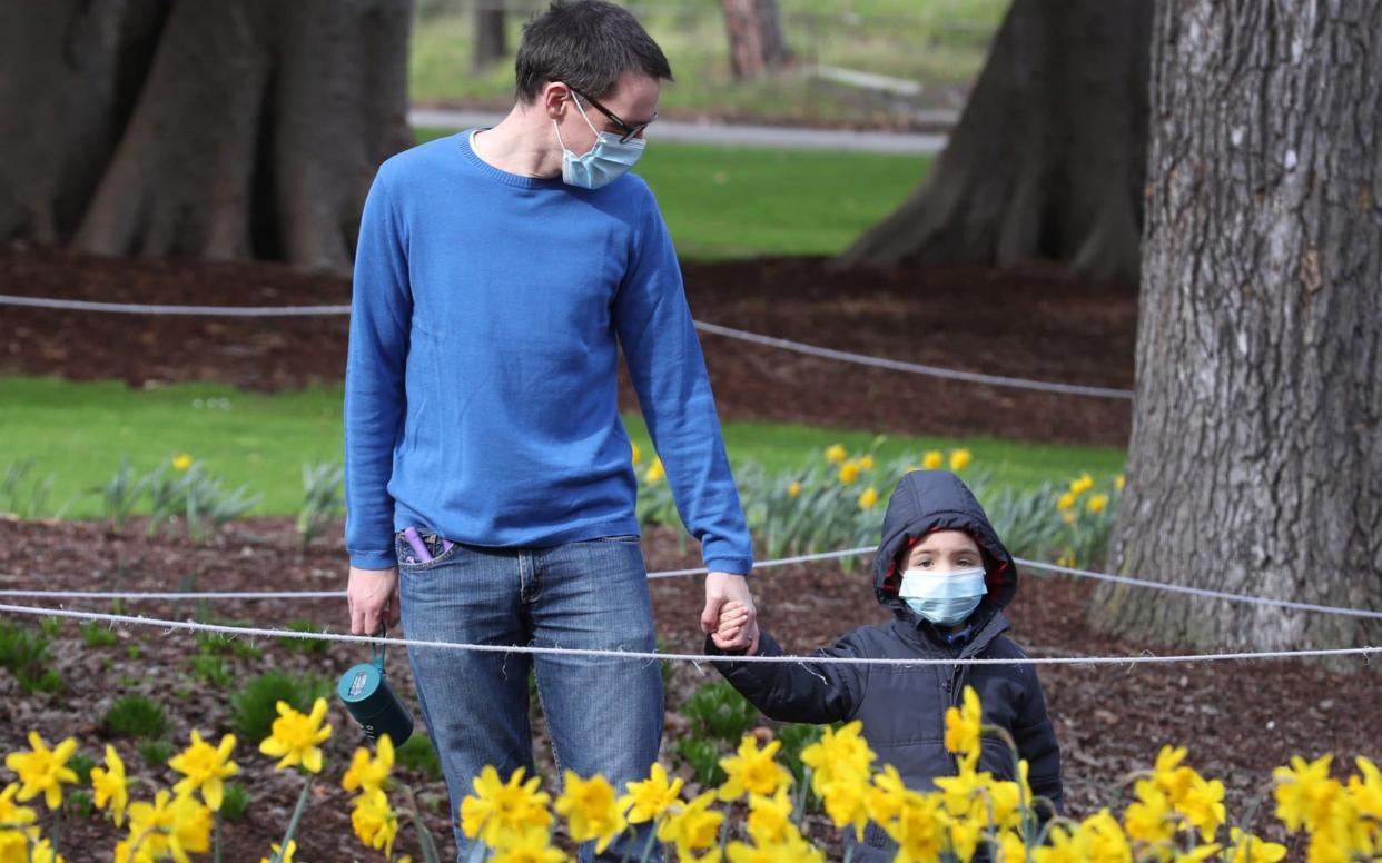 A man and a child, both wearing a face mask, walk at Fitzroy Gardens in East Melbourne, Victoria - DAVID CROSLING/EPA-EFE/Shutterstock