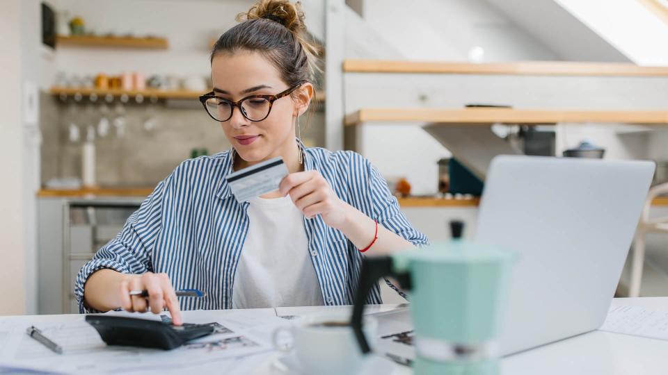 Young woman paying bills/ shopping online with credit card.