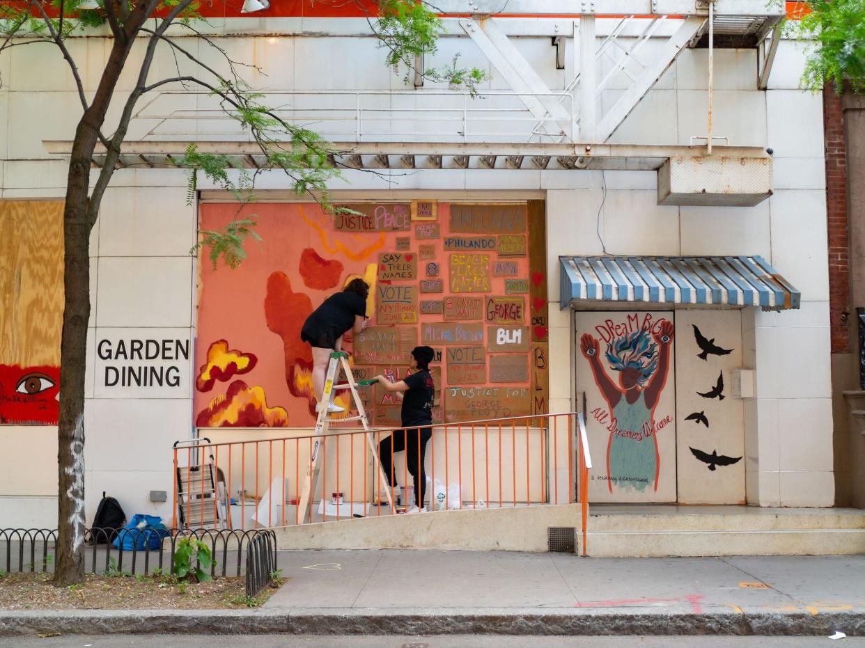 Artists paint on a boarded-up building amid coronavirus closures and protests in the East Village on June 19, 2020 in New York City.