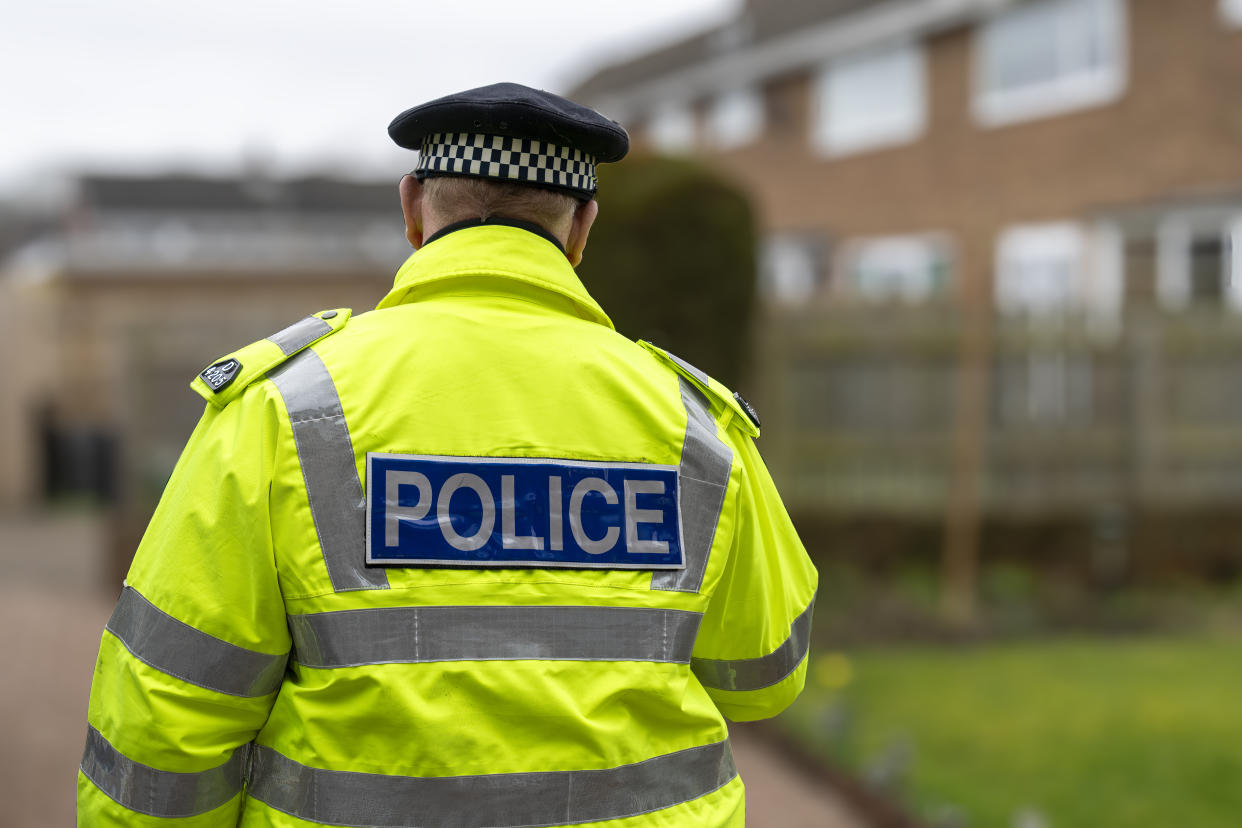 A policeman walking away from an elderly person's home.