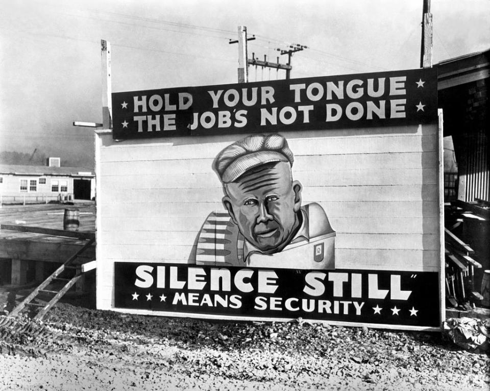 Sign that reads, "Hold your tongue. The job's not done. Silence still means security."