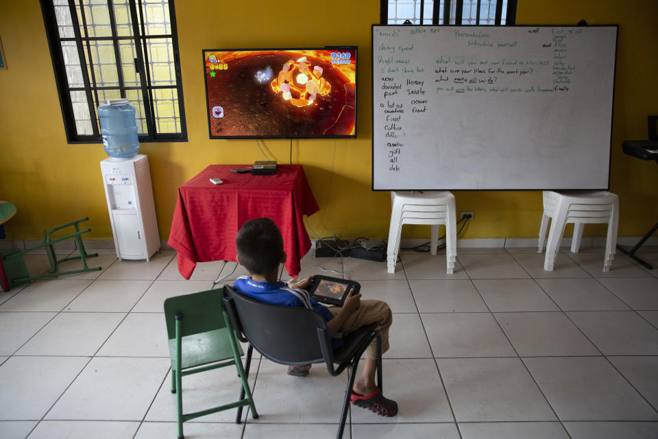 A boy plays video games inside a help center for young people living in dangerous zones, in the Rivera Hernandez neighborhood of San Pedro Sula, Honduras, on Dec. 2, 2019. (AP Photo/Moises Castillo)