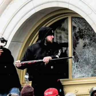 This photo, alleged to be Jordan R. Mink of Allegheny County, Pennsylvania, shows Mink using a baseball bat to shatter the window that many people later climbed through to get into the U.S. Capitol.