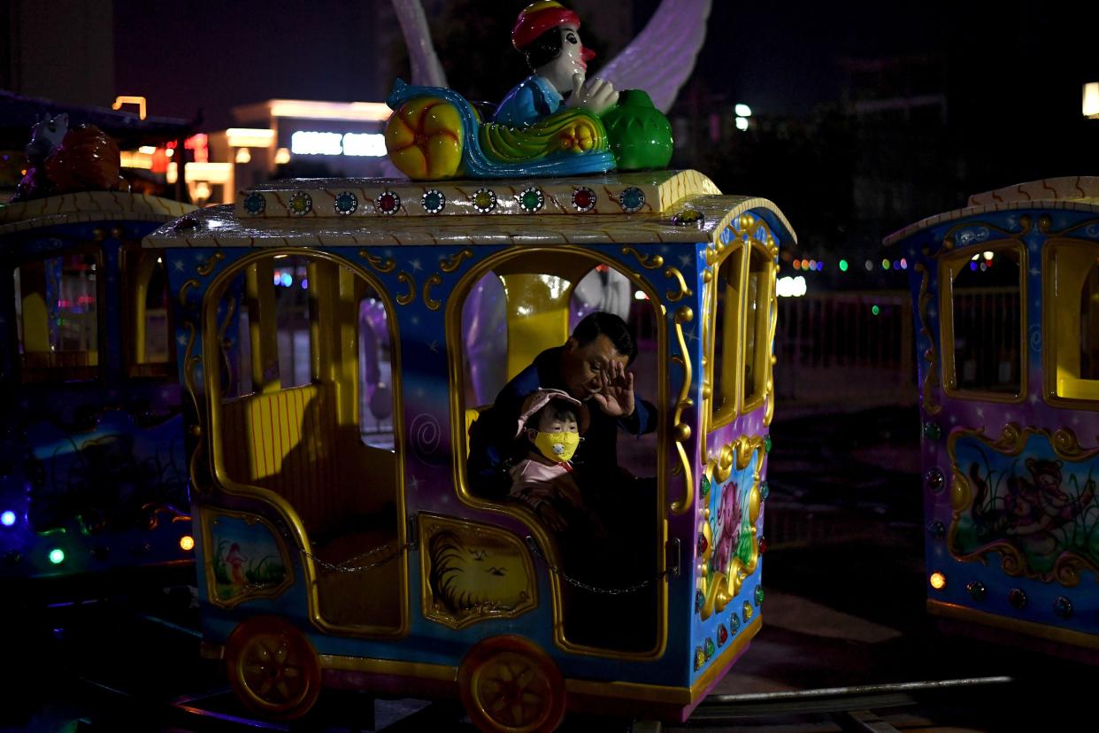 A child wears a face mask alongside his father on a ride at a theme park, following a months-long lockdown - as a preventive measure against coronavirus - is slowly lifted in Macheng, Hubei province, China on March 25, 2020. China lifted tough restrictions on the province at the epicenter of the coronavirus outbreak on March 25 after a months-long lockdown as the country reported no new domestic cases.