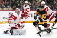 Pittsburgh Penguins' Michael Bunting (8) goes after a rebound off of Detroit Red Wings goaltender Alex Lyon (34) before scoring during the second period of an NHL hockey game in Pittsburgh, Sunday, March 17, 2024. (AP Photo/Gene J. Puskar)