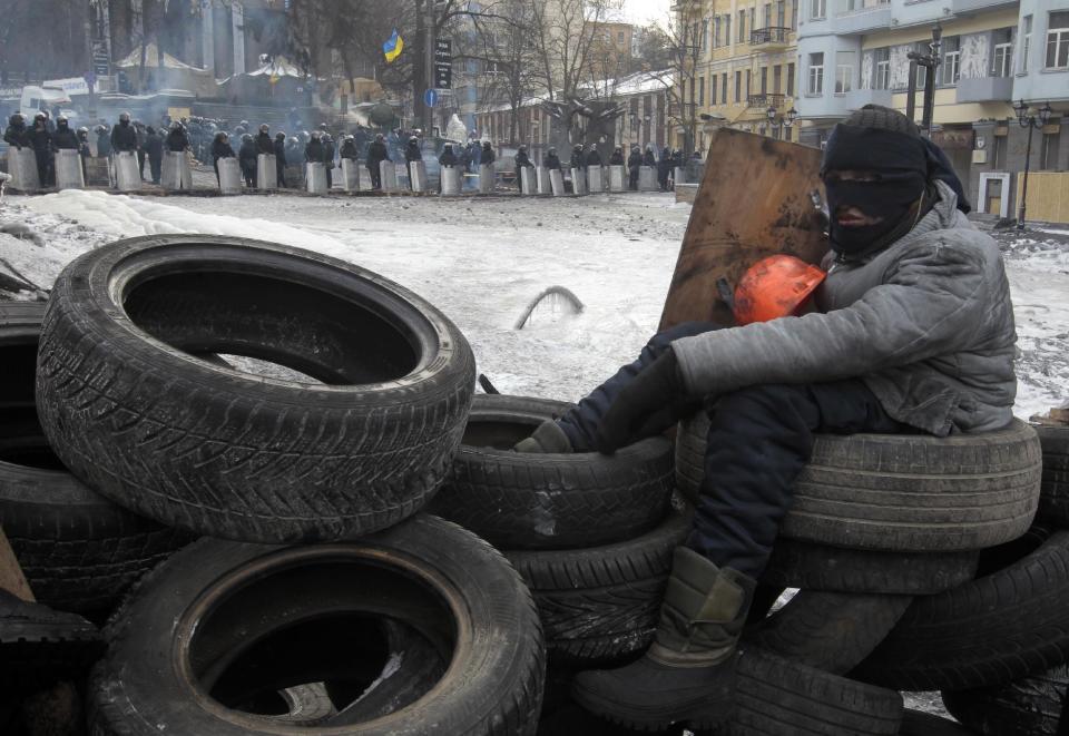 A protester mans the barricade in front of riot police in Kiev, Ukraine, Saturday, Feb. 1, 2014. Ukraine's embattled president Viktor Yanukovych is taking sick leave as the country's political crisis continues without signs of resolution.(AP Photo/Sergei Chuzavkov)