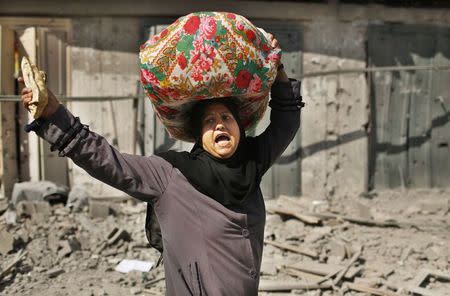 A Palestinian woman reacts as she carries her belongings from her destroyed house in Beit Hanoun town, which witnesses said was heavily hit by Israeli shelling and air strikes during an Israeli offensive, in the northern Gaza Strip July 26, 2014. REUTERS/Suhaib Salem