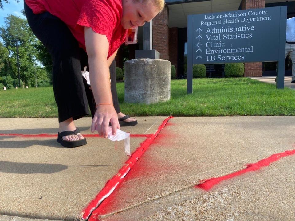 Amanda Johnson, health educator at the Jackson-Madison County Regional Health Department, poured red sand into the cracks of the department's sidewalks to draw attention to the victims that “fall through the cracks” of society.