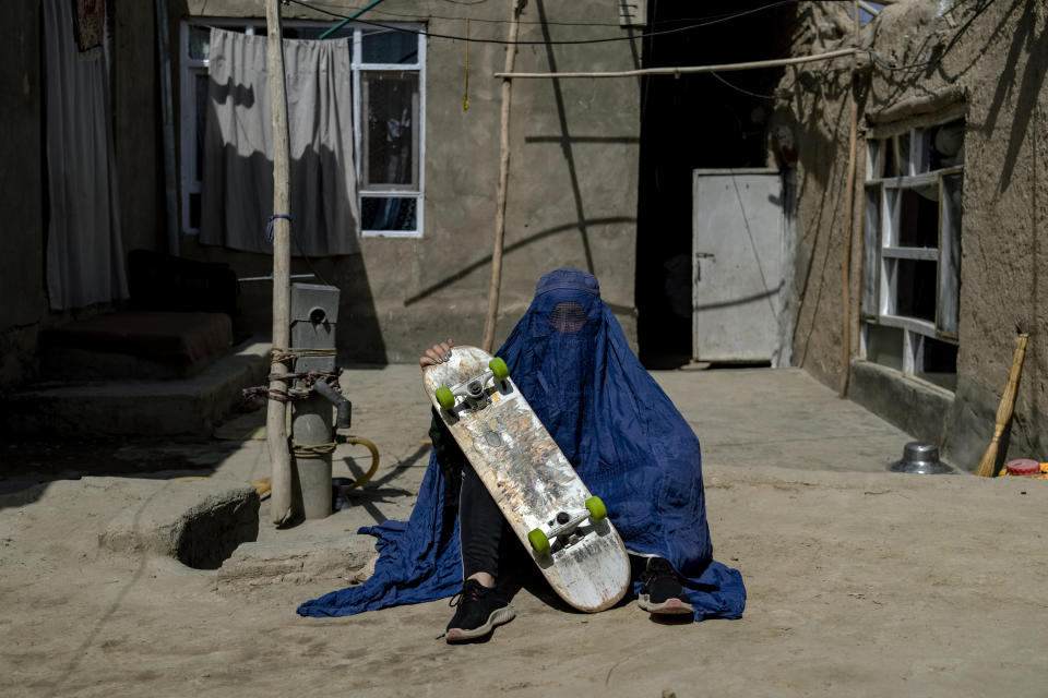 An Afghan girl poses with her skateboard in Kabul, Afghanistan, Saturday, Sept. 10, 2022. The ruling Taliban have banned women from sports as well as barring them from most schooling and many realms of work. A number of women posed for an AP photographer for portraits with the equipment of the sports they loved. Though they do not necessarily wear the burqa in regular life, they chose to hide their identities with their burqas because they fear Taliban reprisals and because some of them continue to practice their sports in secret. (AP Photo/Ebrahim Noroozi)