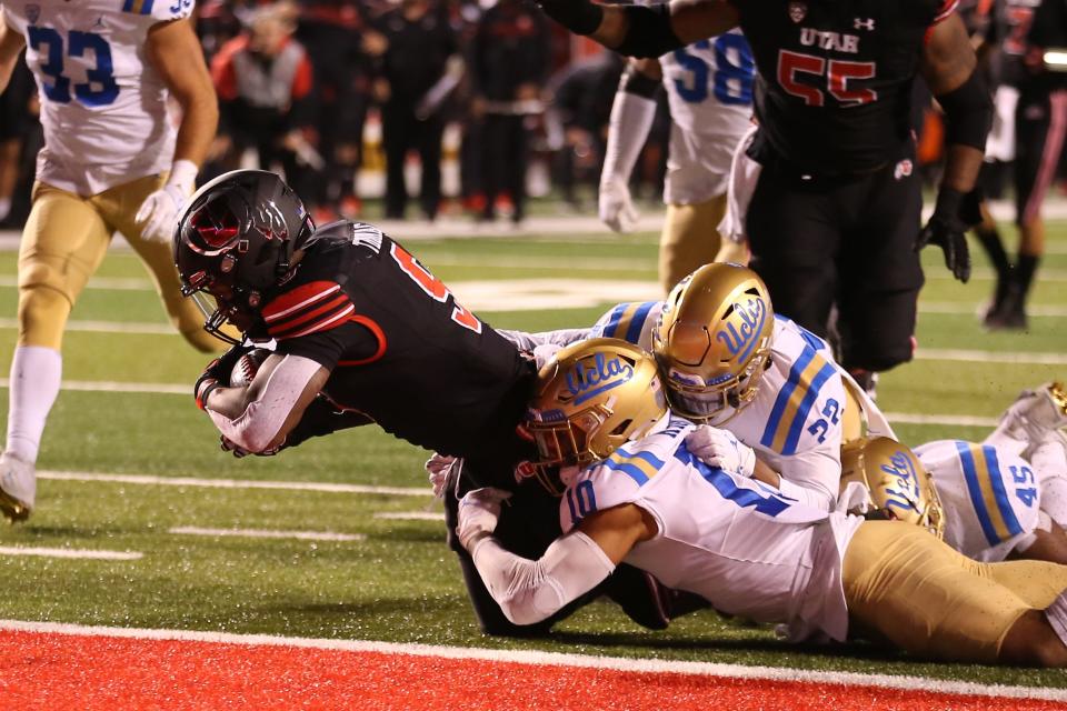 Utah running back Tavion Thomas (9) falls in for a touchdown while defended by UCLA linebacker Ale Kaho (10) and linebacker Jeremiah Trojan (52) during their game 2021 at Rice-Eccles Stadium.