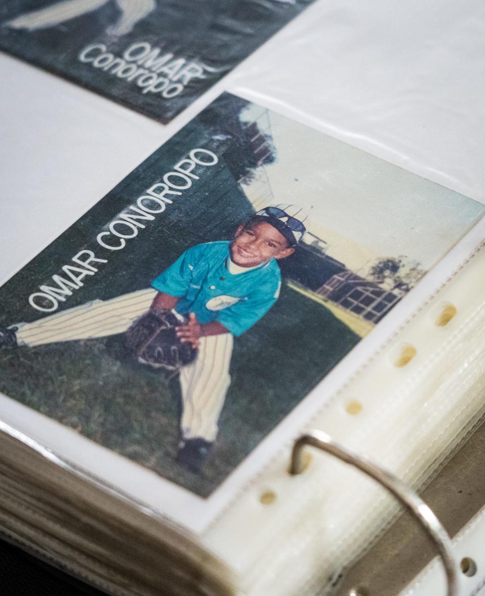 Una fotografía de Omar “Mao” Conoropo en su juventud se muestra en una carpeta llena de fotografías y recuerdos de la infancia de los hermanos Conoropo jugando béisbol en Venezuela.