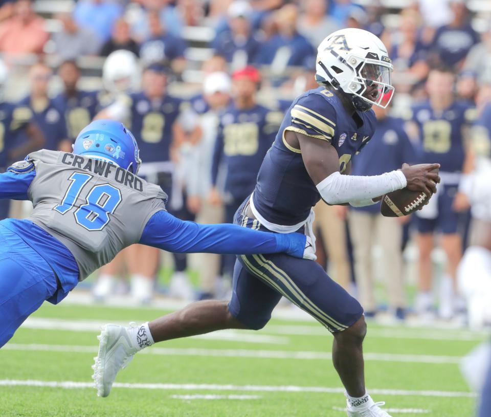 University of Akron quarterback DJ Irons gets past Buffalo linebacker Dion Crawford on Saturday in Akron.