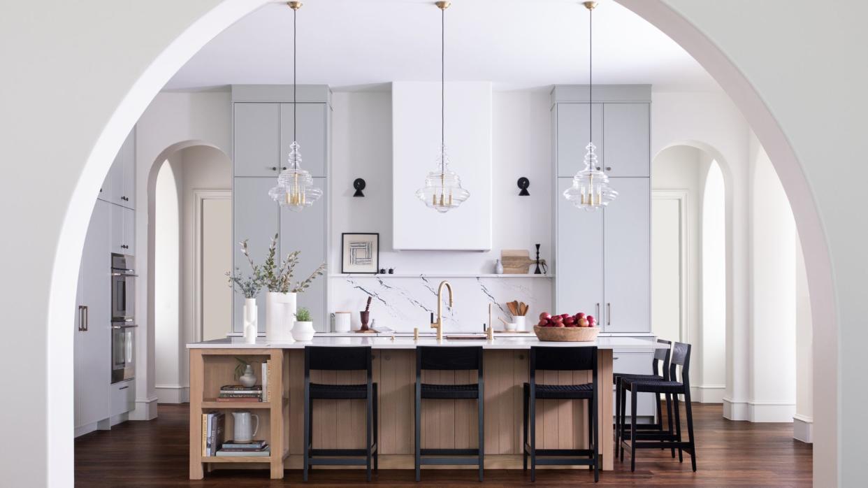  Light kitchen with very tall ceiling and arched entryway. 