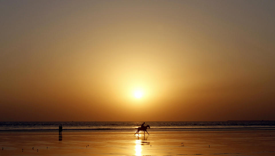 <p>A Pakistani man rides a horse along the beach of Karachi, Pakistan as the sun sets, Jan. 2, 2013. (AP Photo/Shakil Adil) </p>