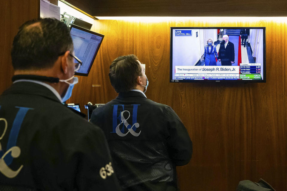 In this photo provided by the New York Stock Exchange, traders watch as the presidential inaugural plays on a screen, in a booth on the trading floor, Wednesday, Jan. 20, 2021. U.S. stocks are rallying to records Wednesday on encouraging earnings reports and continued optimism that new leadership in Washington will mean more support for the struggling economy. (Colin Ziemer/New York Stock Exchange via AP)