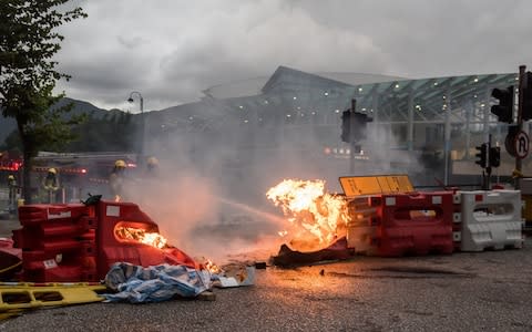 Firefighters extinguish a fire at a road block during a protest in Hong Kong - Credit: Paul Yeung/Bloomberg