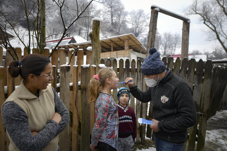 A little boy watches Valeriu Nicolae showing a girl how to correctly brush her teeth in Nucsoara, Romania, Saturday, Jan. 9, 2021. The rights activist has earned praise for his tireless campaign to change for the better the lives of the Balkan country’s poorest and underprivileged residents, particularly the children. (AP Photo/Andreea Alexandru)