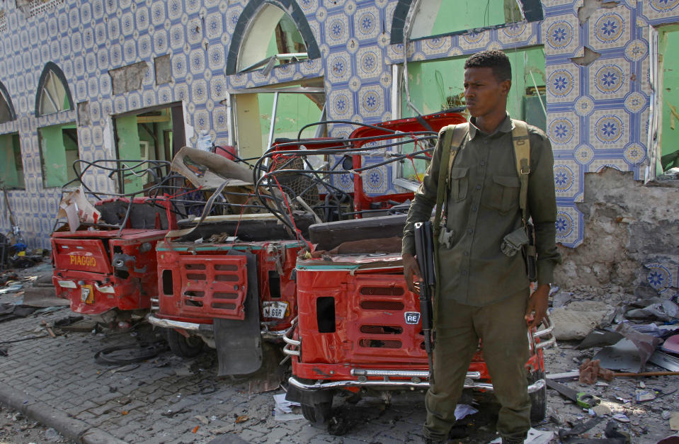 Security forces stand near the wreckage of three-wheeled vehicles destroyed in a bomb attack in the capital Mogadishu, Somalia Saturday, June 15, 2019. (AP Photo/Farah Abdi Warsameh)