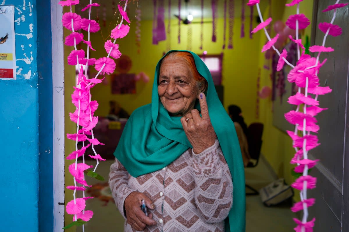 An elderly woman shows the indelible ink mark on her finger after casting her vote (AP)