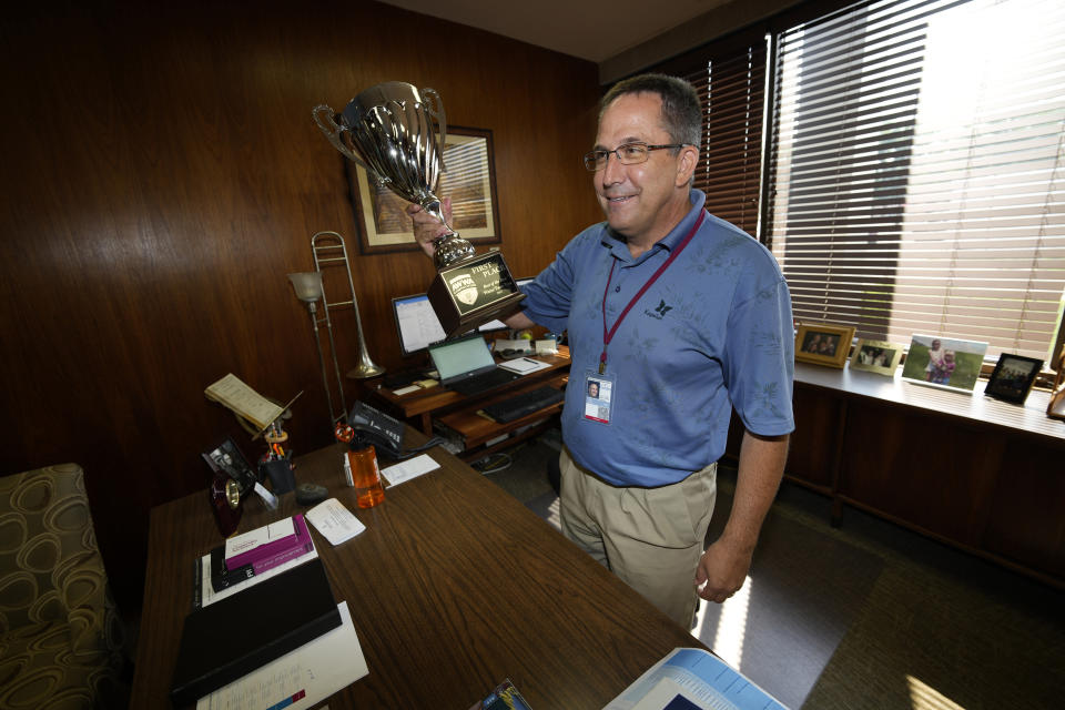 In this Monday, July 26, 2021, photograph, Roy Otto, city manager of Greeley, Colo., holds up a trophy awarded the city for its water as he jokes with reporters in his office in city hall in Greeley, Colo. Figures released this month show that population growth continues unabated in the South and West, even as temperatures rise and droughts become more common. That in turn has set off a scramble of growing intensity in places like Greeley to find water for the current population, let alone those expected to arrive in coming years. (AP Photo/David Zalubowski)