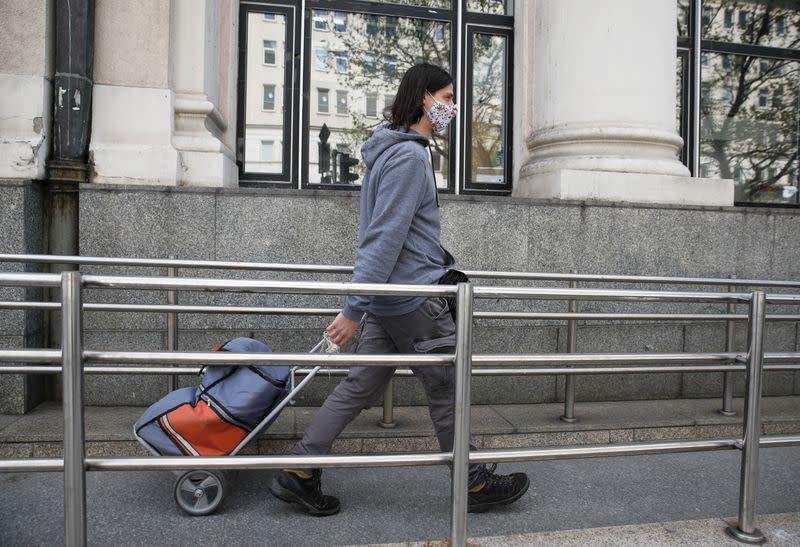 Postman wearing a protective mask walks with a bag in Warsaw