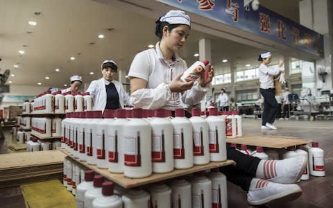 Employees arrange bottles of Moutai baijiu at the Kweichow Moutai Co. factory in the town of Maotai in Renhuai - Credit: Qilai Shen/Bloomberg