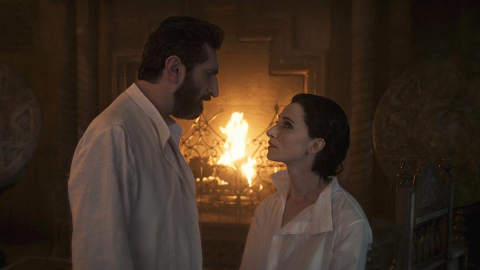 Ishamael and Lanfear face each other wearing white button-down shirts standing in front of a fire