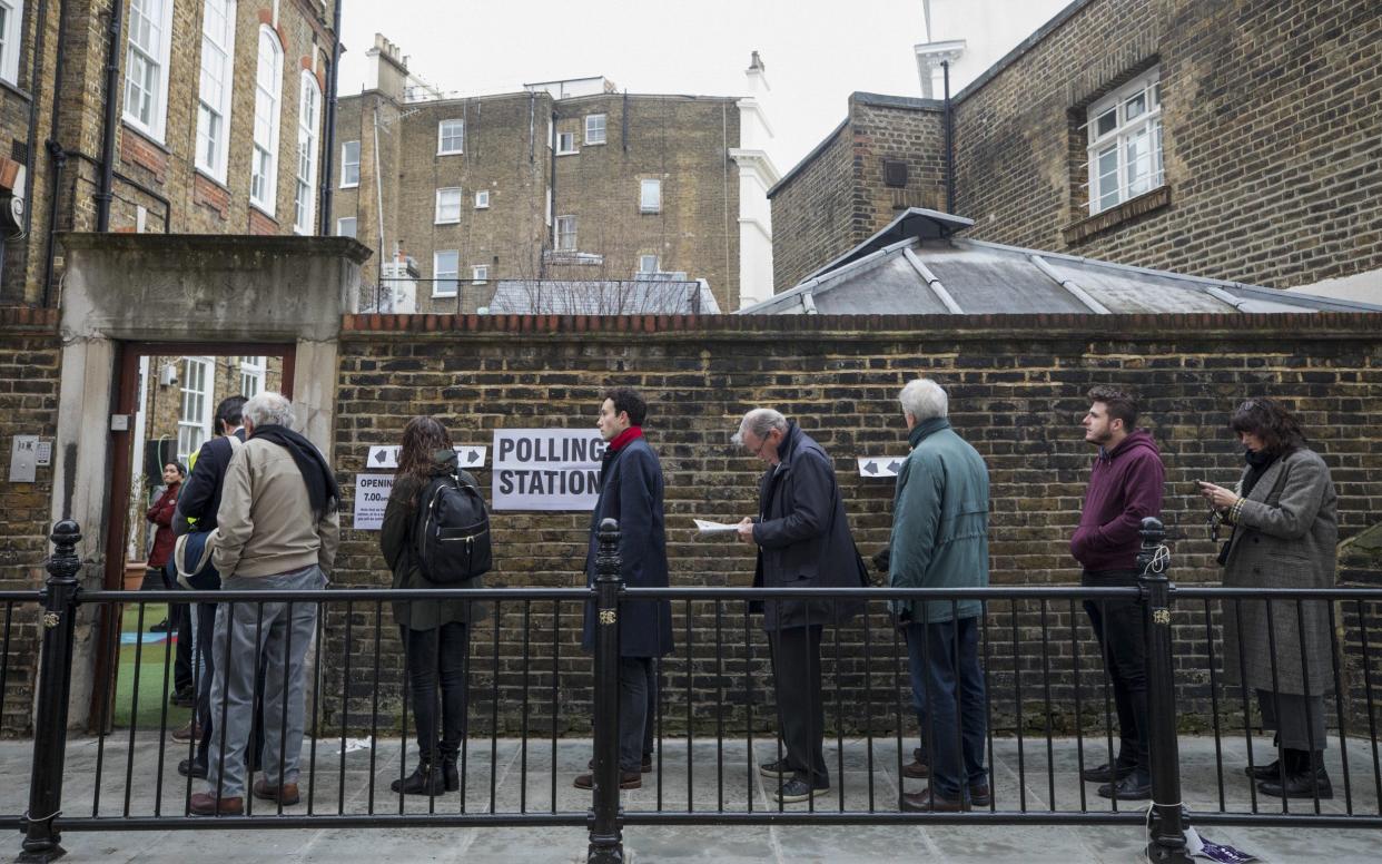 Pedestrians stand in line to enter a polling station in Kensington, west London - Bloomberg