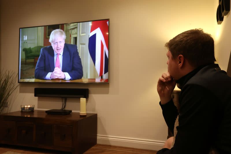 FILE PHOTO: A man watches British Prime Minister Boris Johnson's press conference as the spread of coronavirus disease (COVID-19) continues in Newcastle-under-Lyme