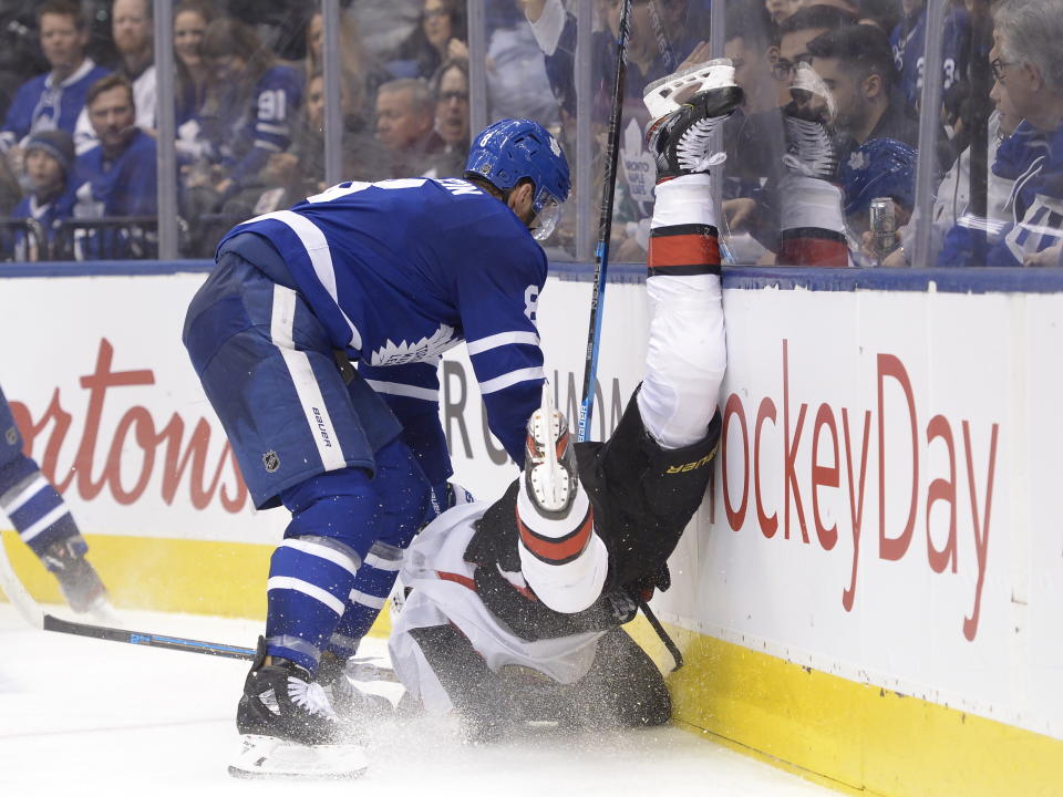 Toronto Maple Leafs defenceman Jake Muzzin (8) hits Ottawa Senators left wing Brady Tkachuk (7) into the boards during third period NHL hockey action in Toronto, Saturday, Feb. 1, 2020. (Nathan Denette/The Canadian Press via AP)