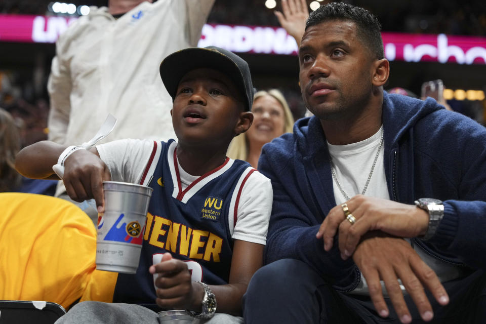 Denver Broncos quarterback Russell Wilson, right, watches during the second half of Game 1 of basketball's NBA Finals between the Denver Nuggets and the Miami Heat, Thursday, June 1, 2023, in Denver. (AP Photo/Jack Dempsey)