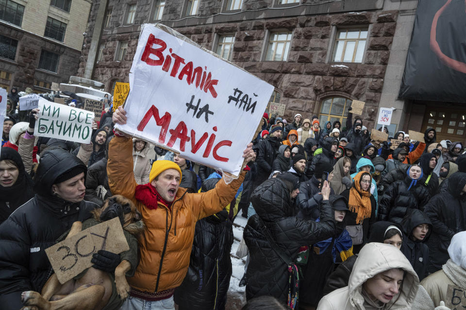 An activist holds a sign reading "Vitali Klitschko gives money for Movic (drone)" during a protest in front of city council of Kyiv, Ukraine, Thursday, Dec. 14, 2023. 500 representatives of the territorial community of Kyiv and the "Money for the Ukrainian Armed Forces" initiative group came to the protest to support the Security and Defense Forces of Ukraine from the budget of Kyiv, which is filled at the expense of taxpayers, subventions and other revenues. (AP Photo/Evgeniy Maloletka)