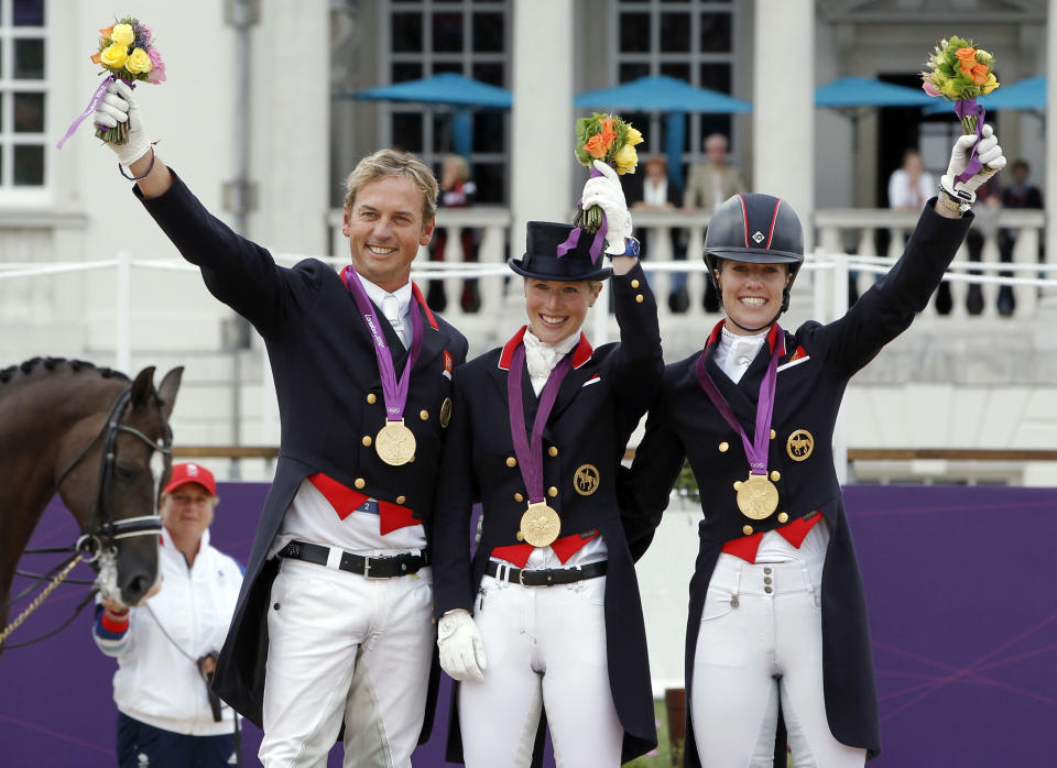 Gold medallists Britain's Carl Hester, Laura Bechtolsheimer and Charlotte Dujardin (L-R) hold up their bouquets during the equestrian dressage team victory ceremony at the London 2012 Olympic Games in Greenwich Park August 7, 2012. REUTERS/Mike Hutchings (BRITAIN - Tags: SPORT EQUESTRIANISM SPORT OLYMPICS) 