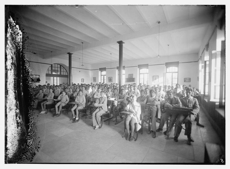 A black and white group photograph of children in a school classroom.