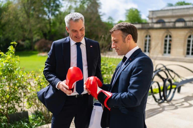 Le chancelier autrichien Karl Nehammer (g), en visite à Paris, offre des gants de boxe au président français Emamnuel Macron, le 4 avril 2024 (Florian SCHROETTER)