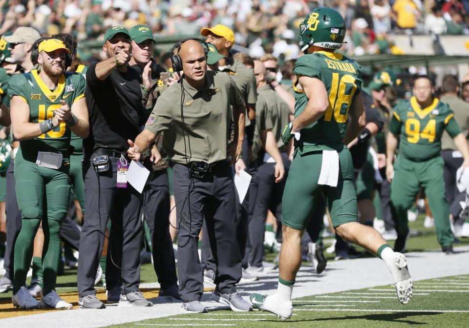 Baylor coach Dave Aranda, left, greets receiver Drew Estrada (18) as he runs off the field