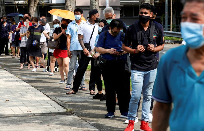 FILE PHOTO: People queue up outside a quick test centre to take their coronavirus disease (COVID-19) antigen rapid tests, in Singapore