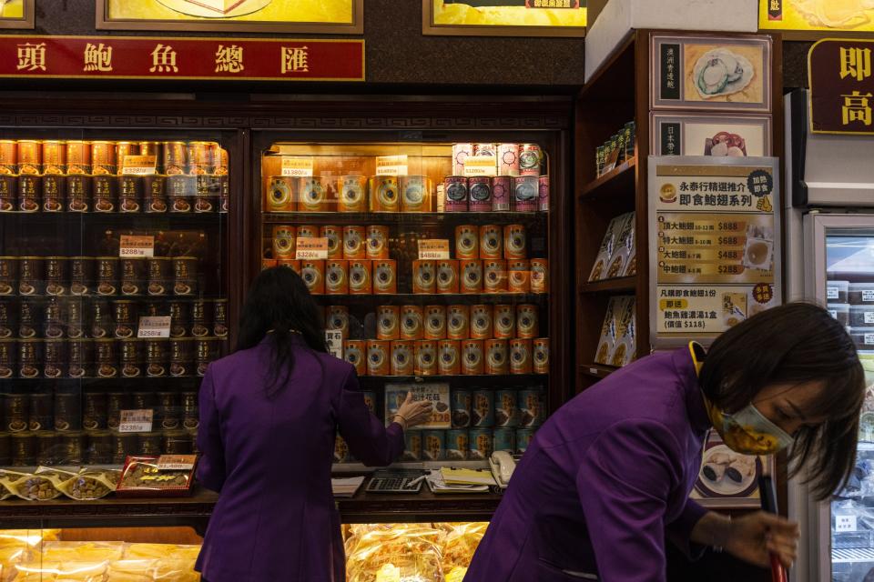 Vendors arrange cans of abalone from South Africa displayed for sale at a shop in Hong Kong, Wednesday, April 12, 2023. Abalone is a sign of prestige or something you would give as a gift in Hong Kong. (AP Photo/Louise Delmotte)